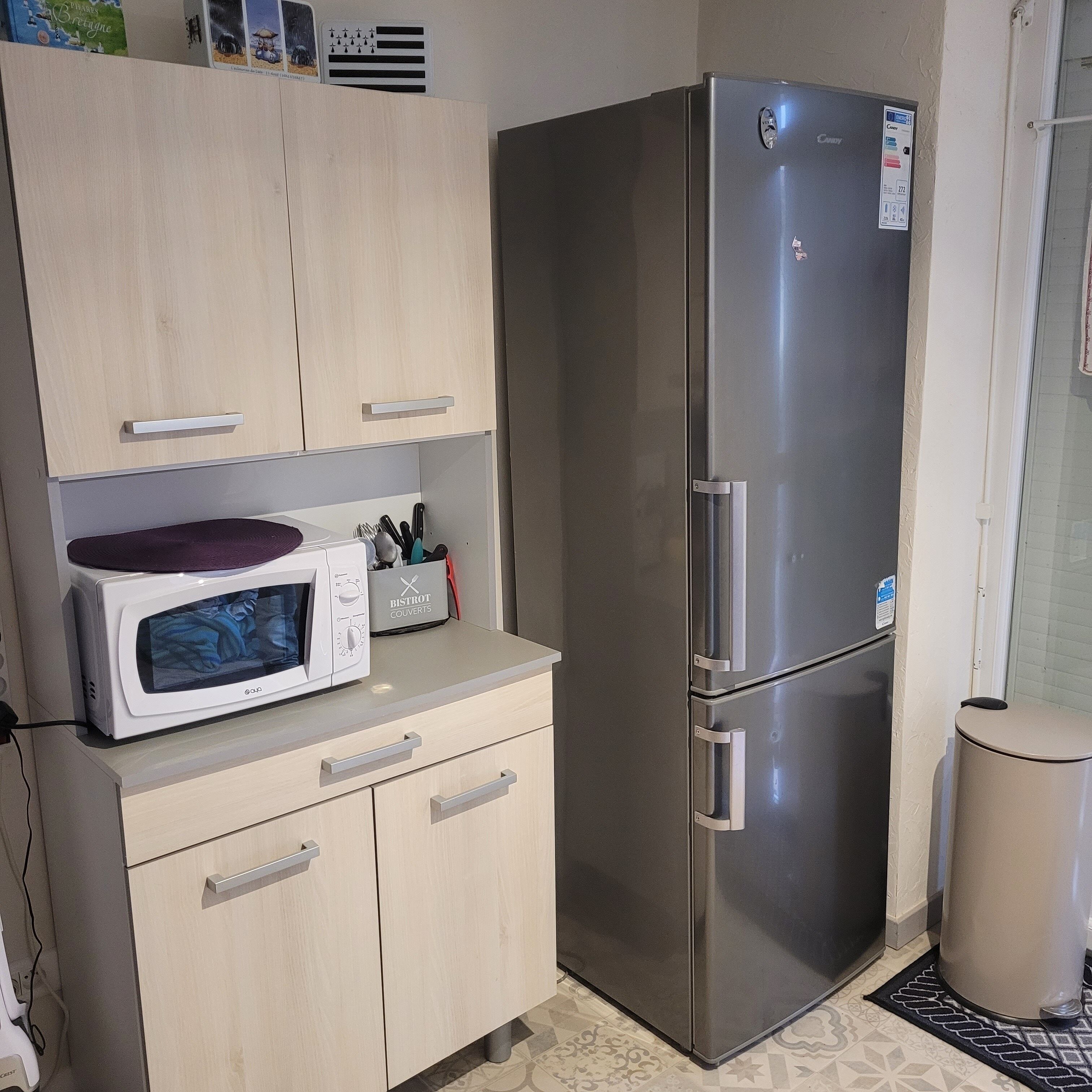 Una cocina con un refrigerador de acero inoxidable, un microondas y un recipiente BISTROT COVERTS.