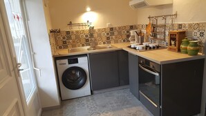 Une petite cuisine équipée d’un lave-linge, d’un évier et d’une cuisinière.