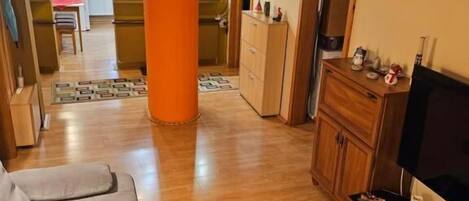 Sala de estar con sofá, una mesa de centro, televisor y una cocina al fondo.