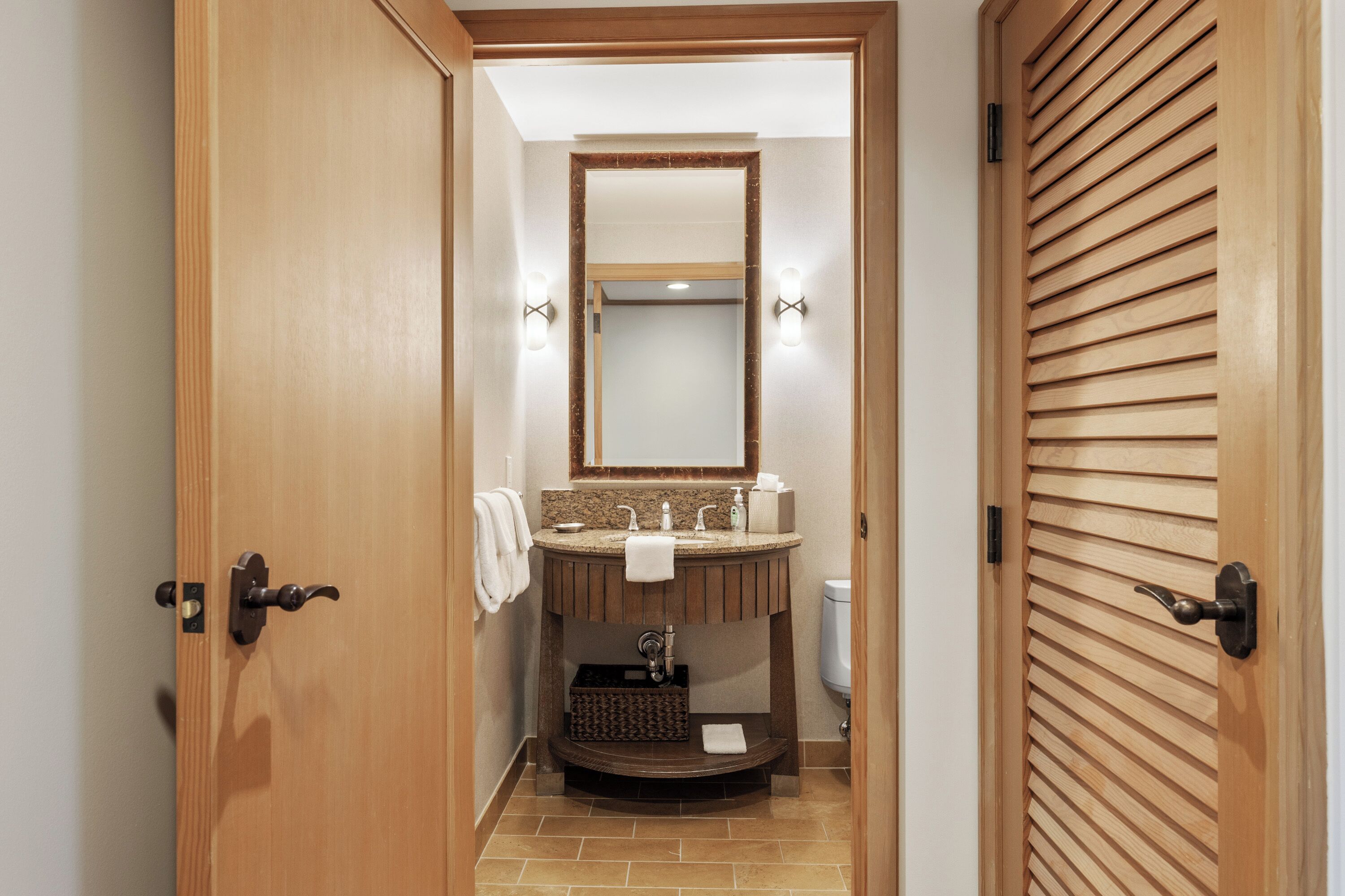 A bathroom with a wooden vanity, a mirror, and a toilet.