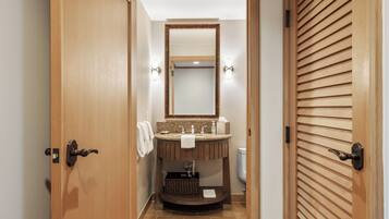 A bathroom with a wooden vanity, a mirror, and a toilet.