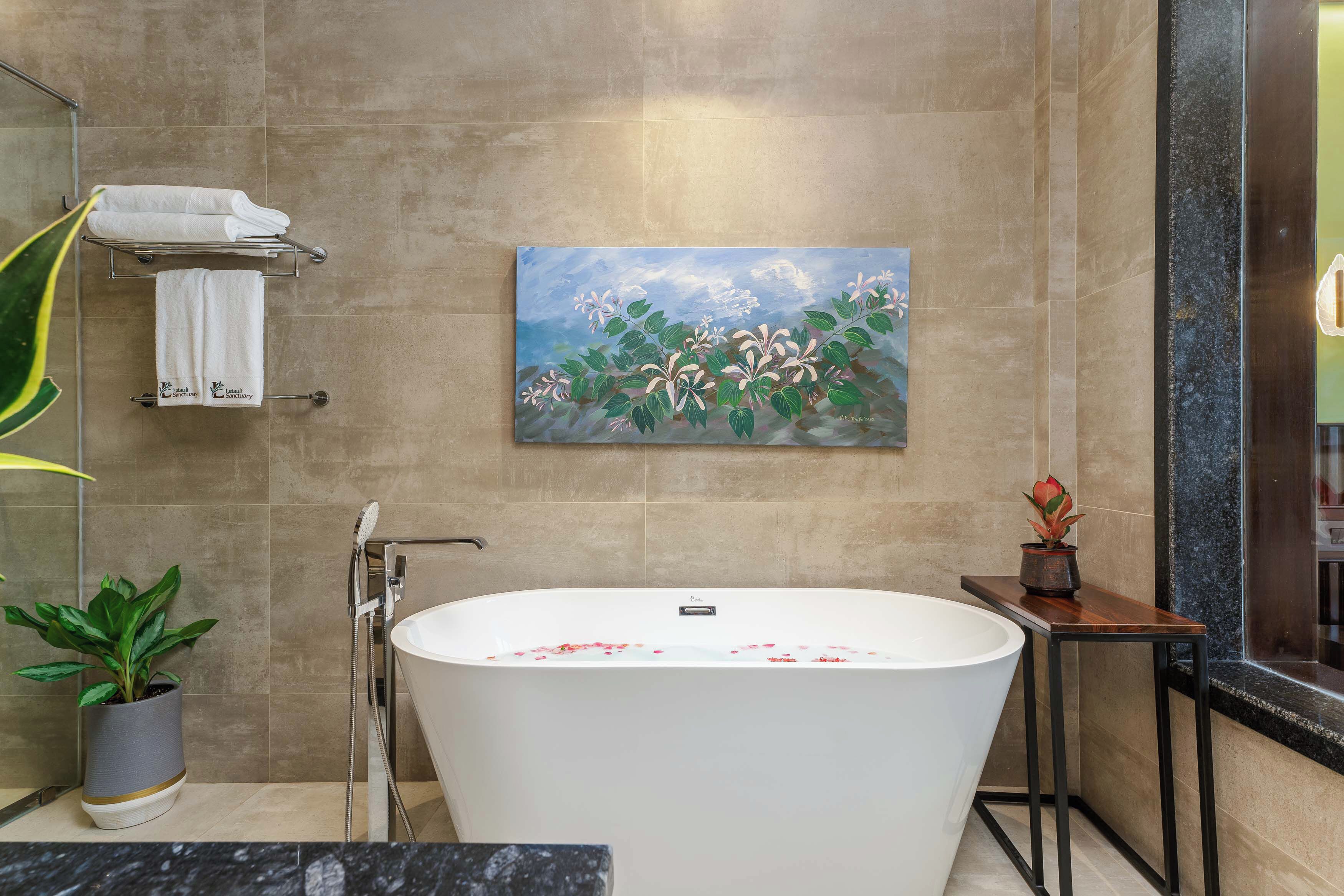 A modern bathroom with a freestanding bathtub, a painting of flowers on the wall, and a potted plant.