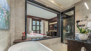 A modern bathroom with a large bathtub, a mirror, and a potted plant. - Latauli Sanctuary (Kalika)