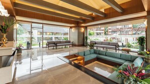 A spacious lobby with a sectional sofa, a coffee table, and a reception desk. - Latauli Sanctuary (Kalika)
