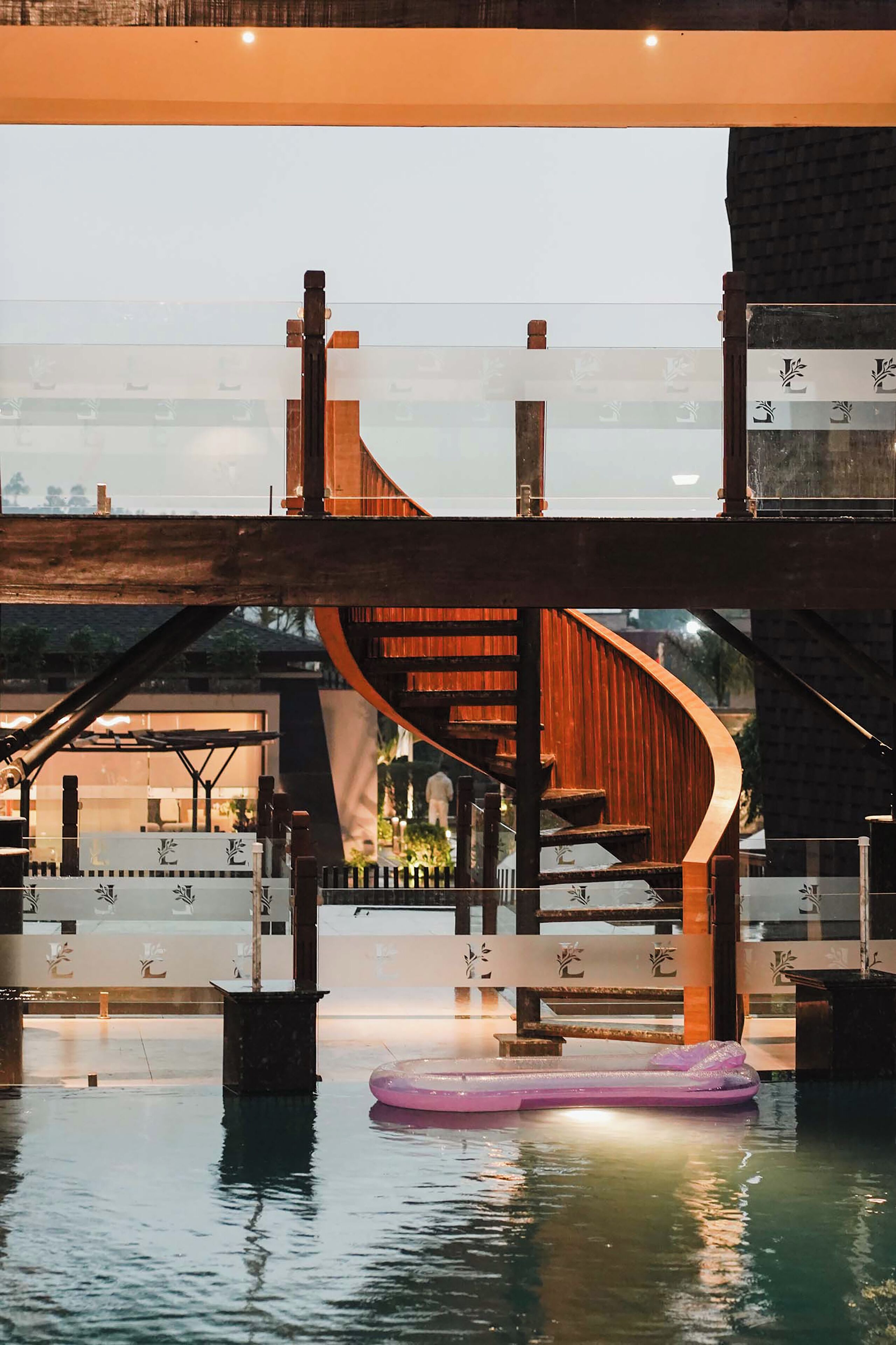 Ein Gewässer mit einer schwimmenden Plattform, einer Holztreppe und einem Gebäude mit einer gewölbten Dachform im Hintergrund.