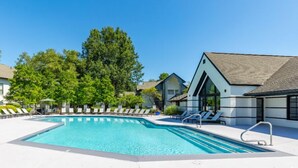 Ein Schwimmbecken mit Liegestühlen und ein Gebäude mit einem geneigten Dach.