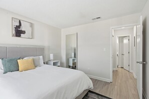 A modern hotel room with a large bed, a bedside table, a mirror, and a wardrobe. - Modern Ease at The Taylor (Louisville)