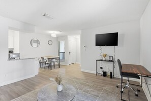 A modern apartment with a kitchen, dining area, and a workspace with a TV. - Modern Ease at The Taylor (Louisville)