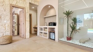 A modern interior with stone walls, a kitchen area with a microwave, and a decorative plant arrangement. - Bungalow Palmeraie-Heated swimming pool not overlooked (Marrakech)