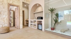 Ein modernes Interieur mit Steinwänden, einer Küchenzeile mit Mikrowelle und einer dekorativen Pflanzengestaltung.