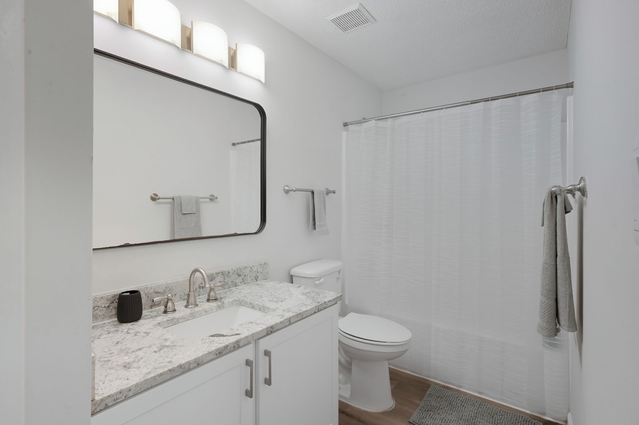 A modern bathroom with a white sink, a toilet, and a shower curtain.