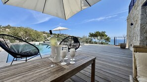Eine Holzterrasse mit einem Tisch, zwei Stühlen und einer Champagnerflasche.