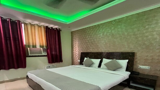 A bedroom with a large bed, a ceiling fan, and a window with curtains. - M K Hotel And Restaurant (Jammu)