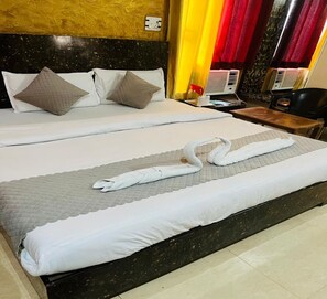 A hotel room with two beds, a marble headboard, and a small table with a chair. - M K Hotel And Restaurant (Jammu)