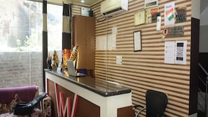 A hotel reception area with a reception desk, a clock, and various posted notices including no smoking and hand wash signs. - M K Hotel And Restaurant (Jammu)