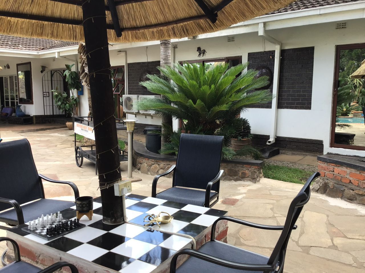 An outdoor seating area with a checkered table, two chairs, and a chessboard.
