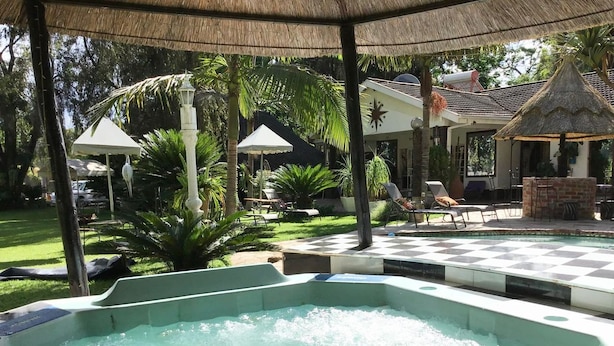 Un bain à remous situé dans un espace extérieur abrité, équipé de chaises longues et de parasols.