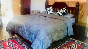 Une chambre à coucher avec un lit, une table de chevet, une tête de lit en bois et un tapis à motifs.