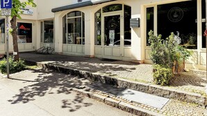 Un caffè chiamato 'Café Stopover' con una insegna, un segnale di parcheggio e l'ingresso di un edificio.