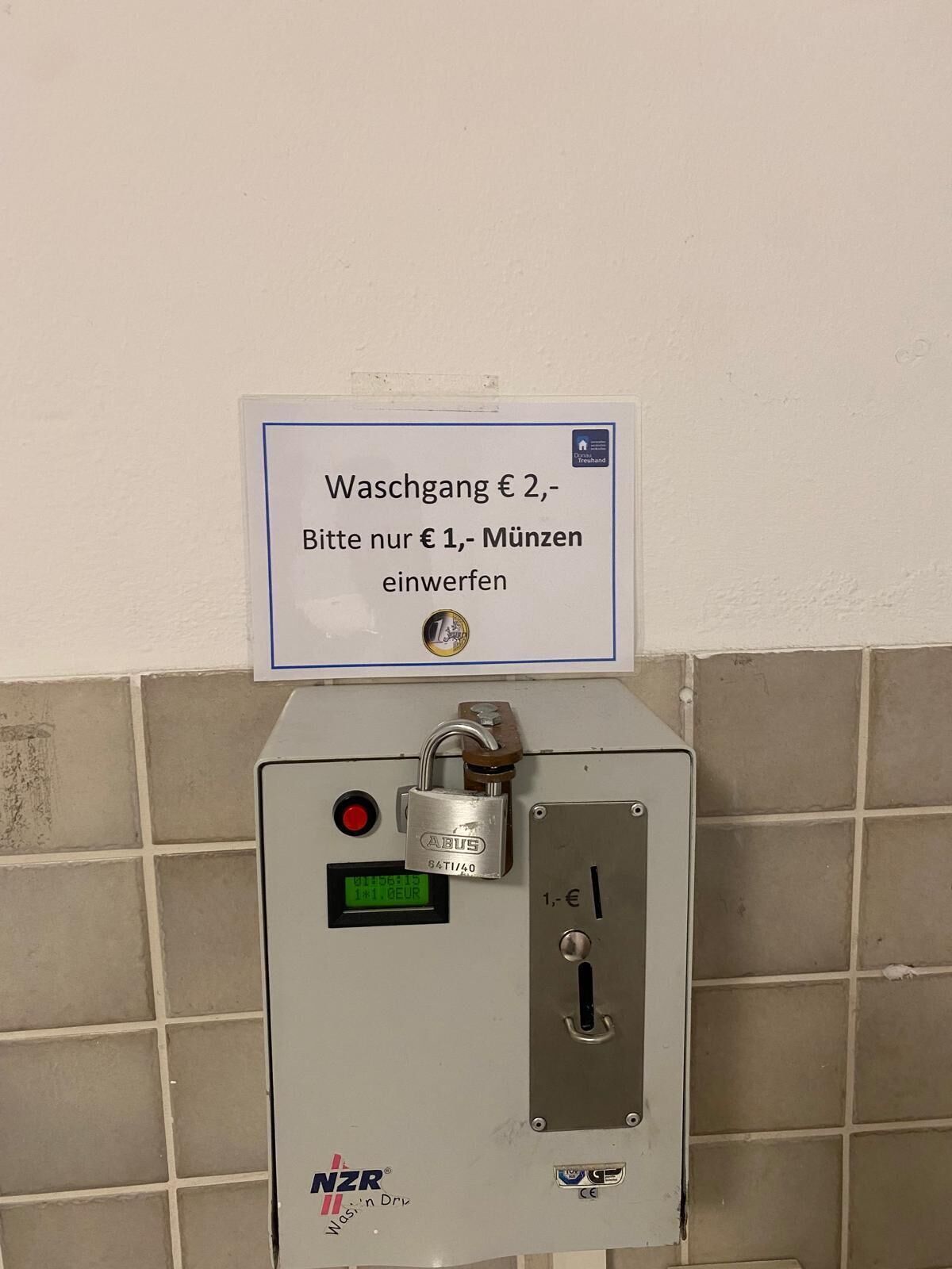 Un baño público con un cartel que indica una tarifa de 2 euros para usarlo y un retorno de 1 euro en monedas.