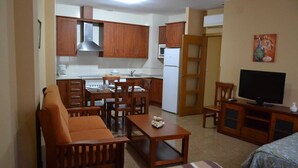 A compact living space with a kitchenette, dining area, and a TV. - Hostal Ruralis Altozano  (Montánchez)