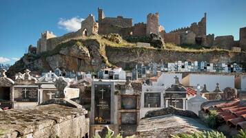 Un cementerio con lápidas y un castillo histórico al fondo.