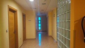 A hallway with wooden doors, a tiled floor, and a glass block wall. - Hostal Ruralis Altozano  (Montánchez)