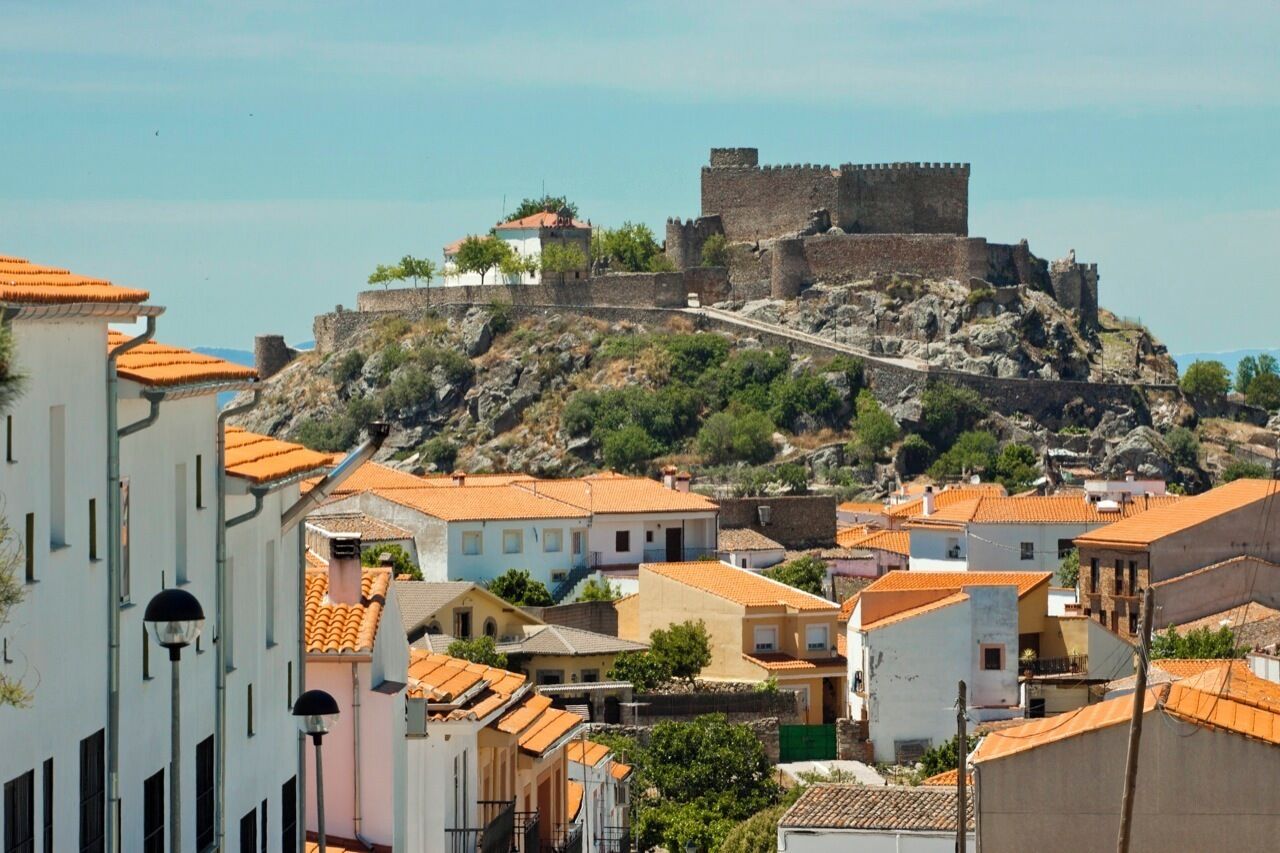 A historic fort on a hill overlooking a town with traditional buildings.