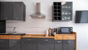 Et moderne køkken med lysegrå skabe, en rustfris stål emfang, en mikrobølgeovn og en kaffemaskine på bordet.