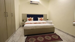 A bedroom with a bed, a nightstand, an air conditioning unit, and a wardrobe. - Hotel Taj Elevate (Agra)