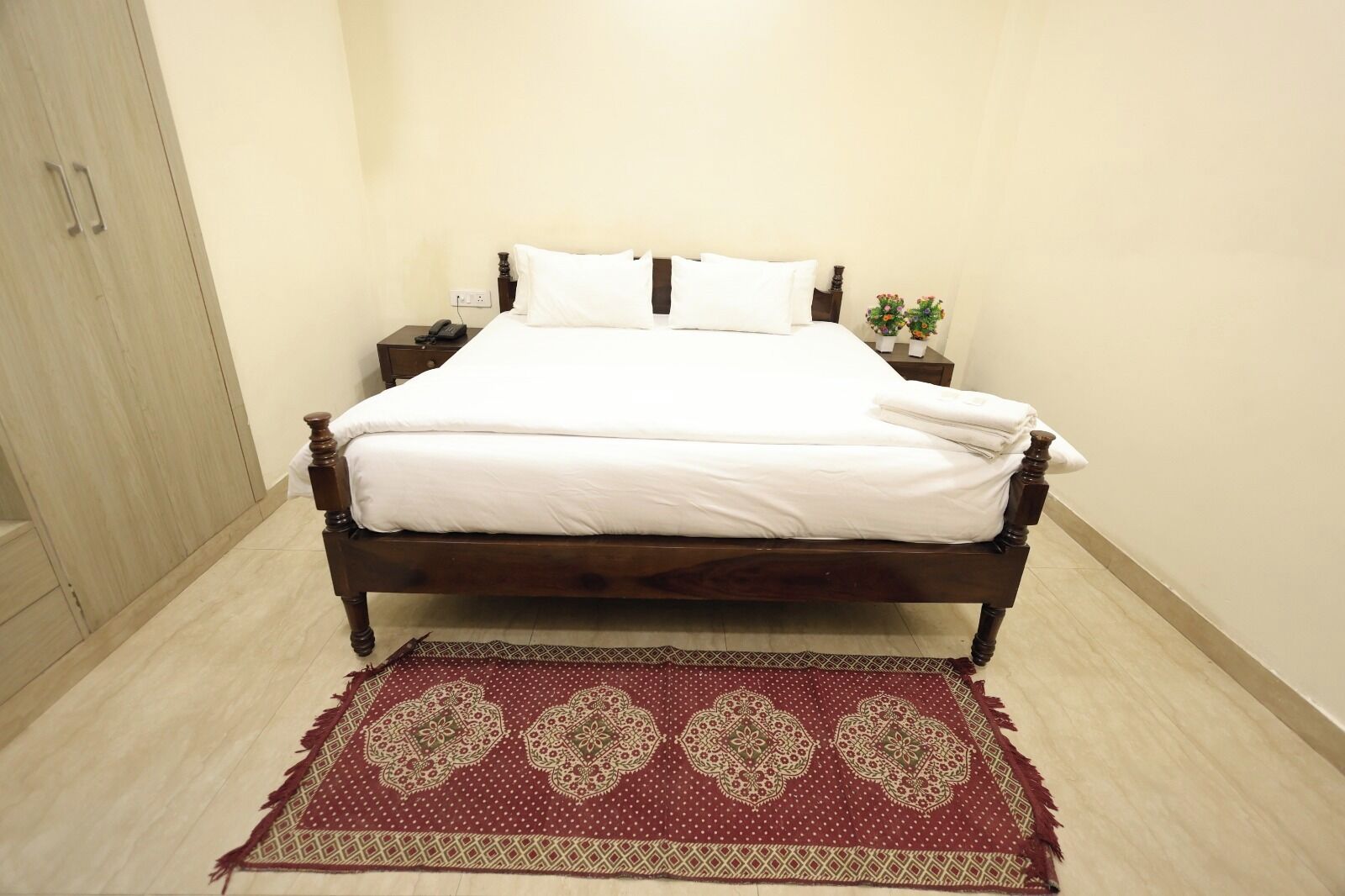 A neatly made bed with white linens, a wooden headboard, and a small bedside table with a lamp.