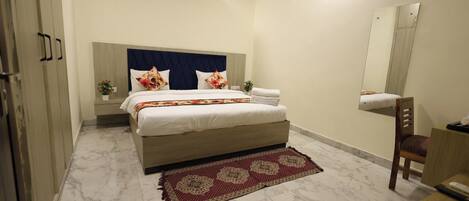 Un dormitorio con cama, mesita de noche, silla, espejo y aire acondicionado.