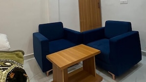 A modern room with a blue sectional sofa, a wooden coffee table, and a wooden cabinet. - Hotel Taj Elevate (Agra)