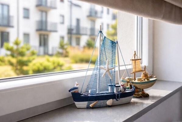 A model sailboat on a windowsill with a view of buildings and greenery outside. - HoliApart Trimare Billard &Seasonal Pool (Sztutowo)
