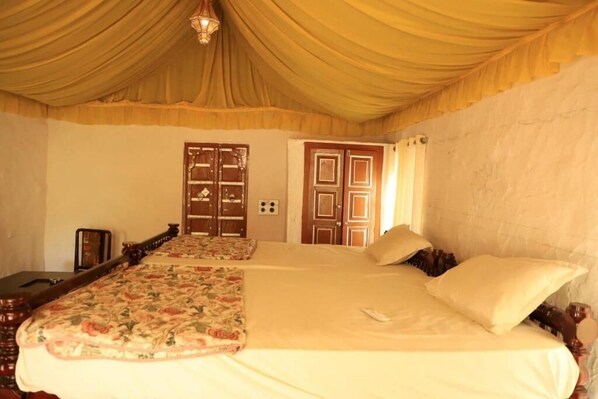 A room with a large bed, two doors, and a chandelier.
