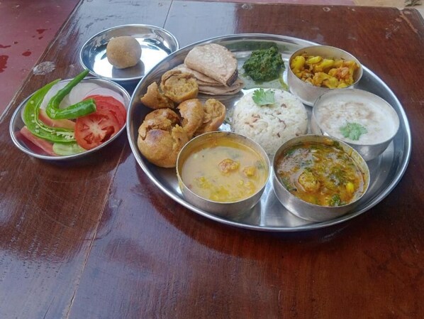 A traditional Indian meal served on a stainless steel plate with various dishes including rice, curry, and bread.