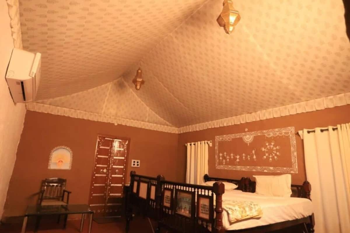 A bedroom with a bed, a chair, a ladder, and a wall-mounted air conditioning unit.