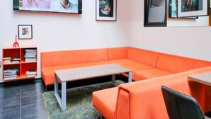 Une pièce moderne avec un canapé orange, une petite table et une bibliothèque.