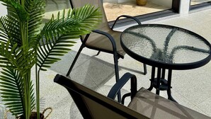 A modern outdoor seating area with a glass door leading to a balcony, surrounded by potted plants. - Top Sea view villa Josephine. Close to Chaweng beach (Koh Samui)