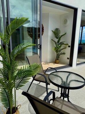 A modern outdoor seating area with a glass door leading to a balcony, surrounded by potted plants. - Top Sea view villa Josephine. Close to Chaweng beach (Koh Samui)