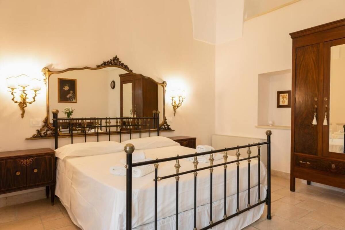 A bedroom with a four-poster bed, a large mirror, and two bedside tables.