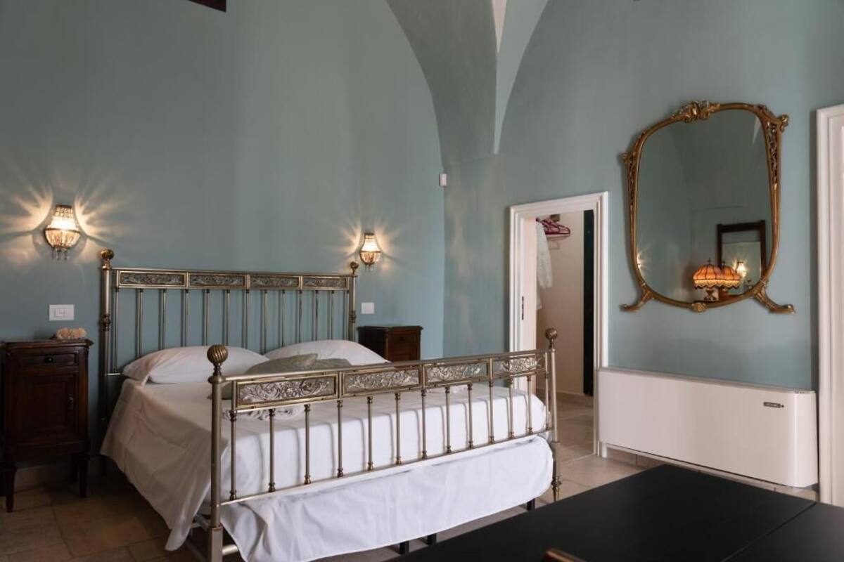 A bedroom with a bed, two bedside tables, a mirror, and a radiator.