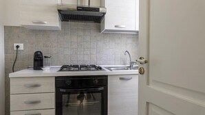 Eine kleine Küche mit Gaskochfeld, Backofen und Kaffeemaschine.