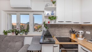 Una cucina moderna con un piano di lavoro nero, mobili bianchi e vista sulla città attraverso ampie finestre.