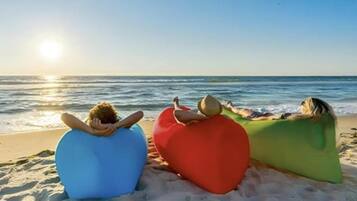 En la playa, arena blanca, sillas reclinables de playa, sombrillas