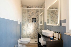 Ein Badezimmer mit Toilette, Waschbecken, Spiegel und Duschbereich.