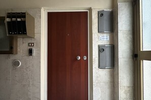 Una habitación con puerta de madera, un respiradero y dos equipos de aire acondicionado en la pared.