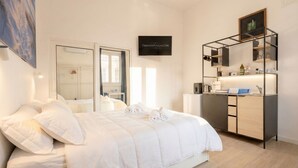 Una habitación de hotel moderna con cama, escritorio, espejo y un cartel enmarcado en la pared.