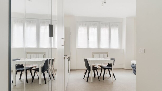 A room with a white table and chairs, a radiator, and a window with curtains. - GuestHost - Comfortable and cozy 35 square meters studio apartment, perfect for two people, located on the ground floor of a building.The property is located near the Gambara M1 metro station (5 minutes' walk), offering quick access to Milan's most centr (Milan)
