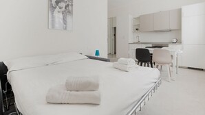 A hotel room with a bed, a desk, a chair, and a kitchenette. - GuestHost - Comfortable and cozy 35 square meters studio apartment, perfect for two people, located on the ground floor of a building.The property is located near the Gambara M1 metro station (5 minutes' walk), offering quick access to Milan's most centr (Milan)